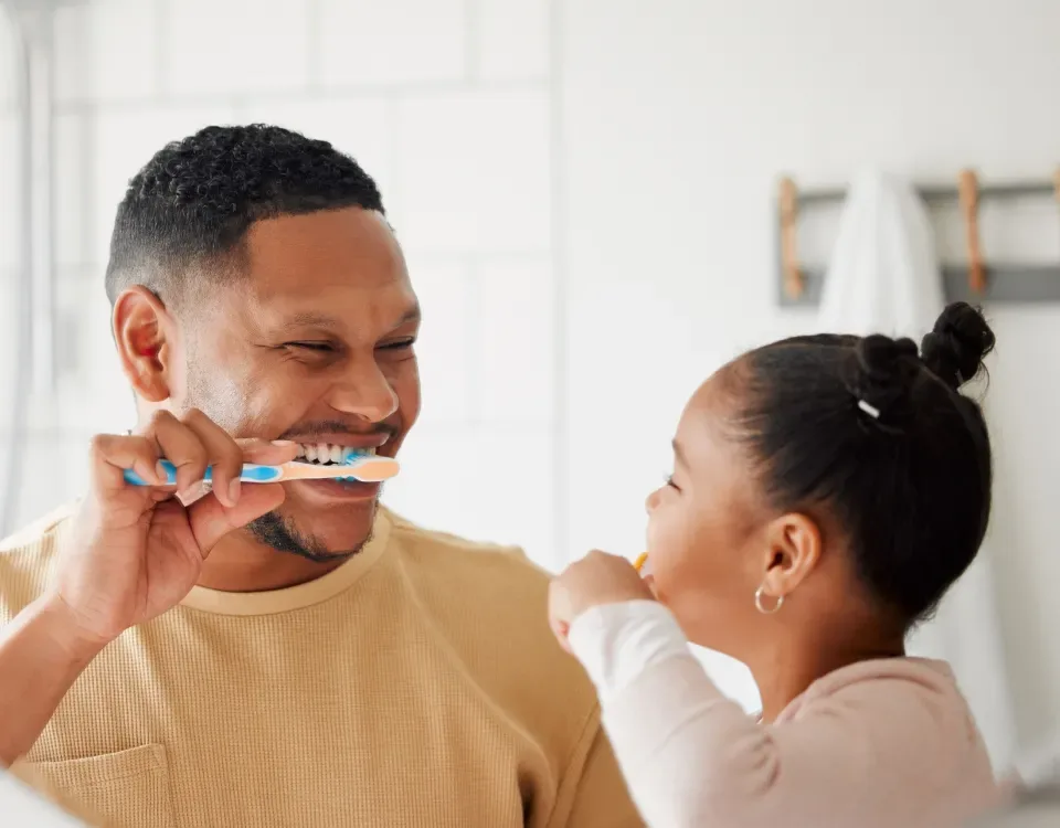 Father and daughter brushing their teeth together