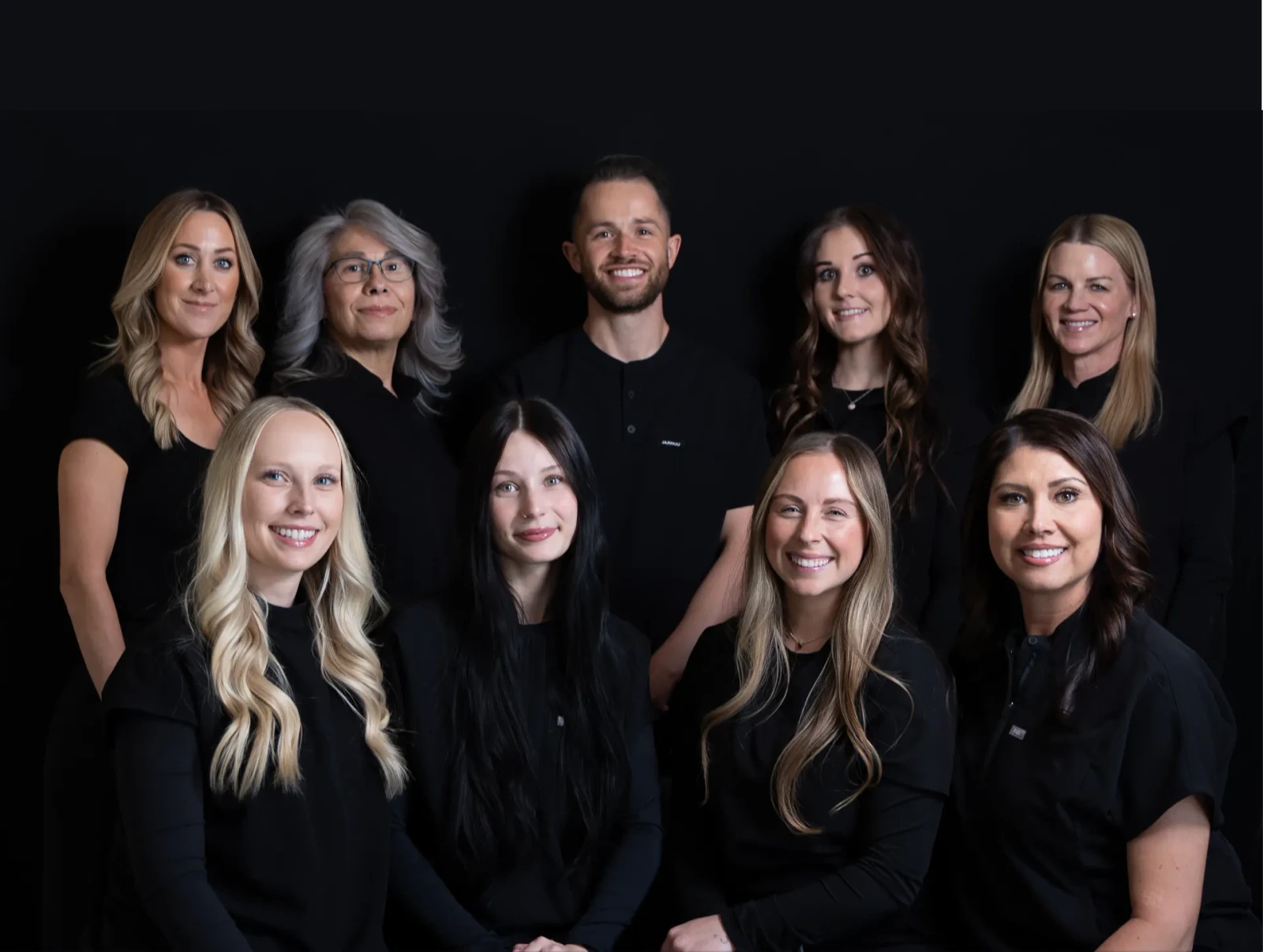 The SoJo Dental team smiling together in matching black uniforms